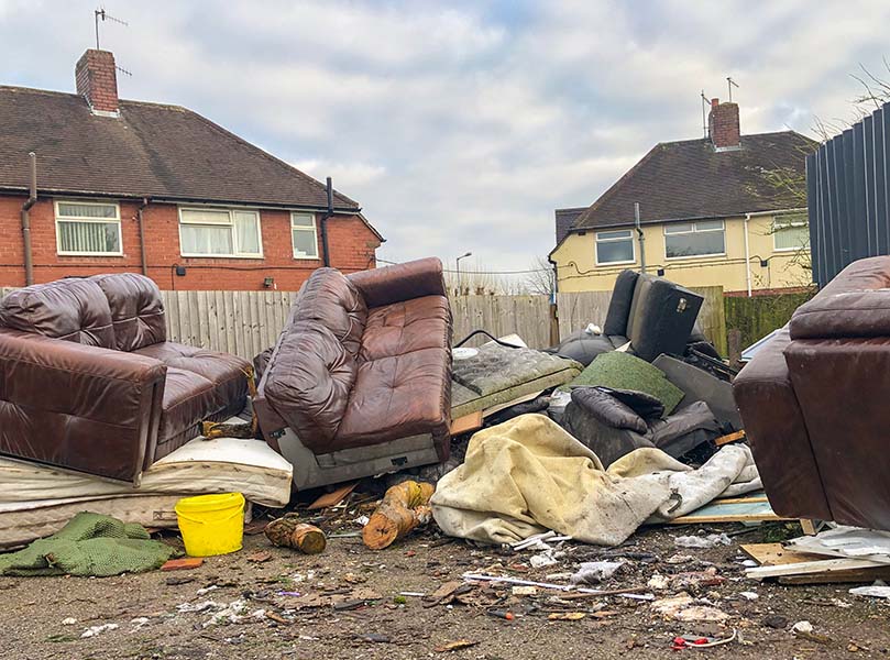 discarded furniture and fly tipped rubbish in a uk housing estate